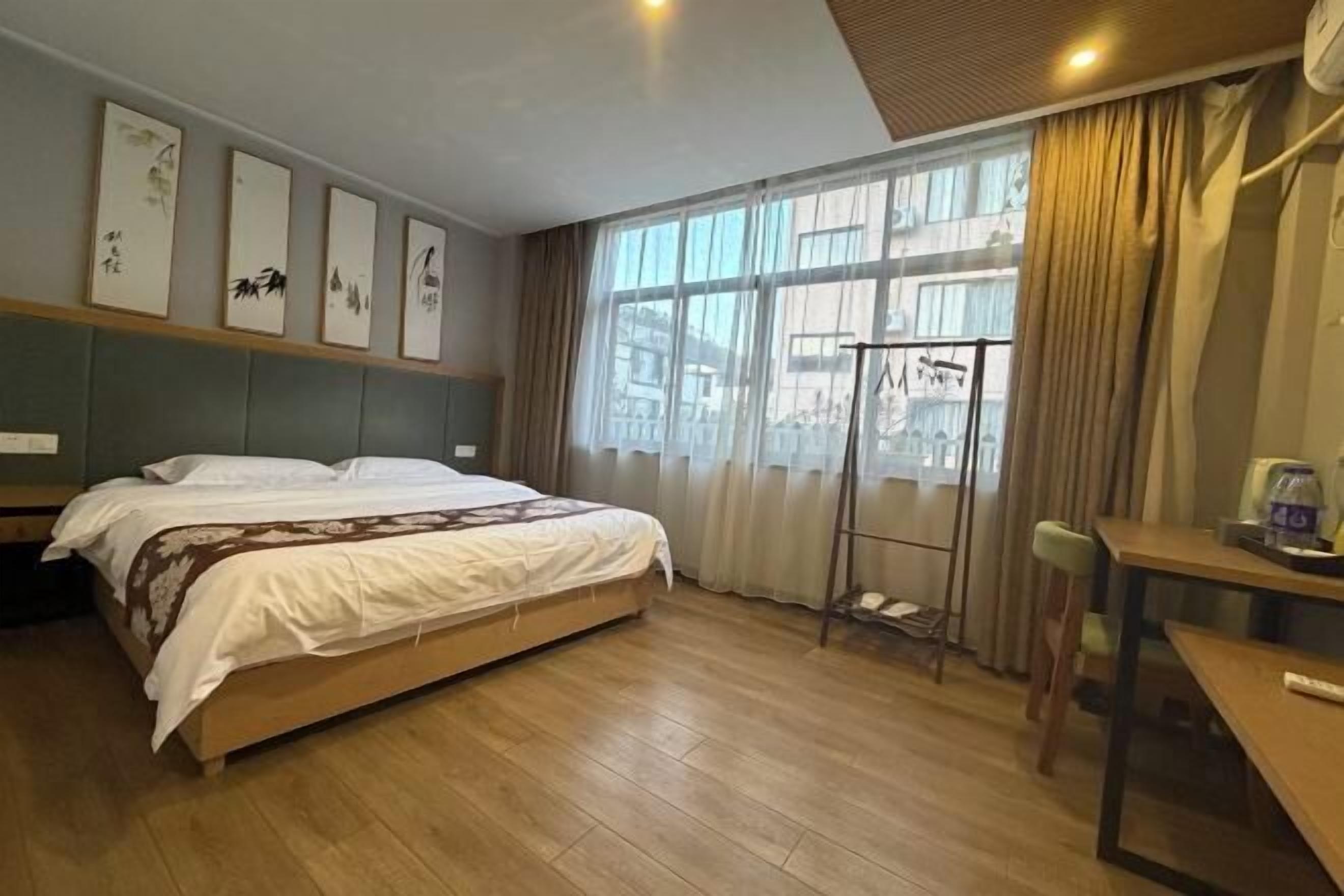 A hotel room with a bed, a desk, and a window with curtains.