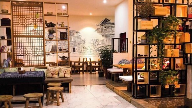 A cozy interior with a seating area, a bookshelf, and a decorative wall. - Migratory Haven · Xishan Hidden Inn (Wuyishan)