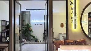 A hotel entrance with a modern design, featuring a glass door, a reception desk, and a seating area with a sofa and cushions. - Migratory Haven · Xishan Hidden Inn (Wuyishan)