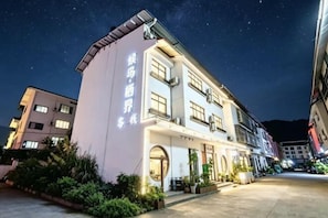 A multi-story hotel with a prominent entrance, a well-lit facade, and a clear night sky. - Migratory Haven · Xishan Hidden Inn (Wuyishan)