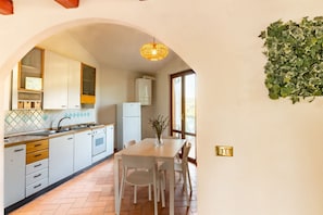 A kitchen with white cabinets, a tiled backsplash, and a dining area with a white table and chairs.