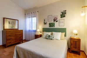 A bedroom with a bed, two bedside tables, a dresser, and a mirror.