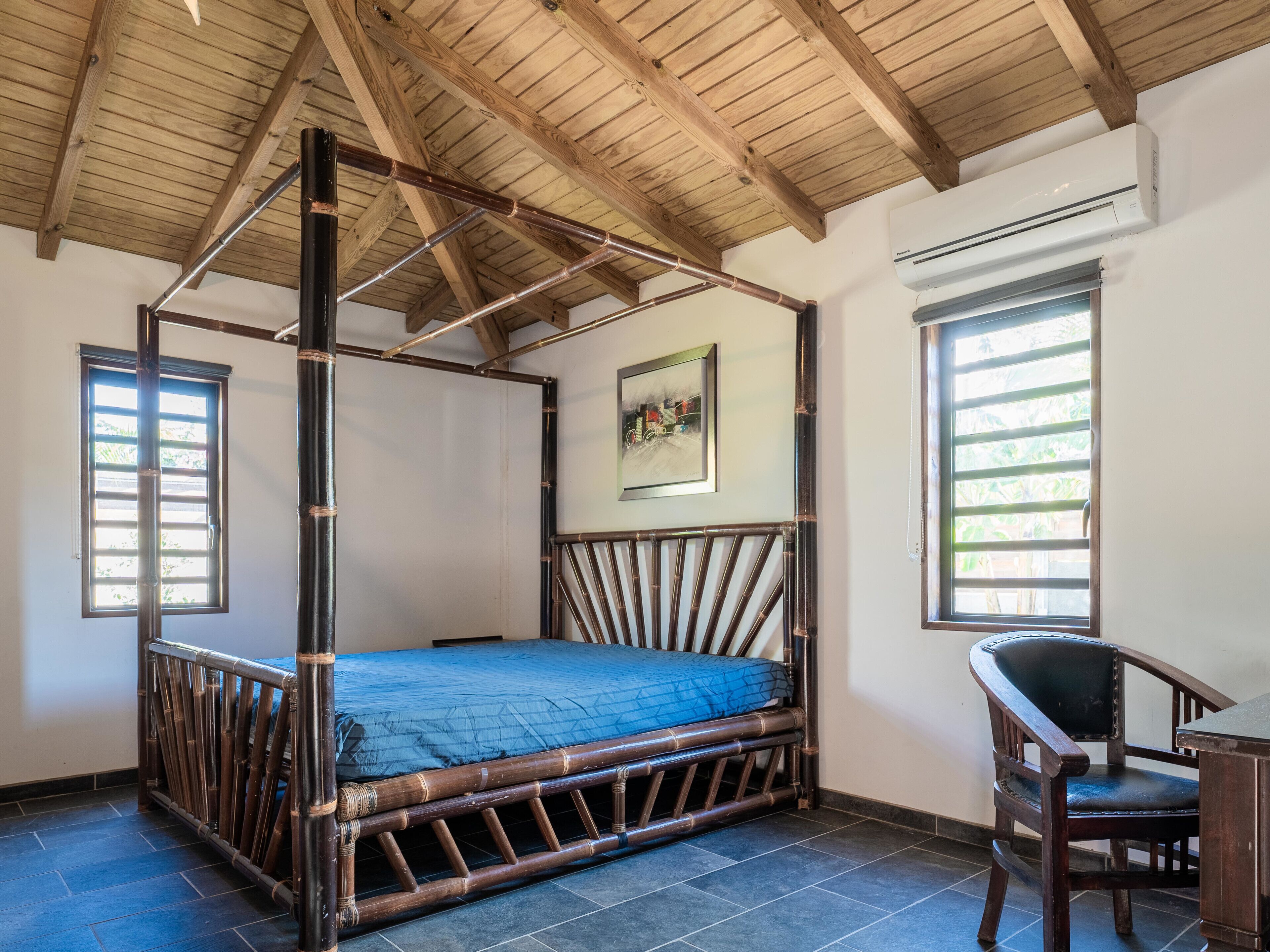 Habitació amb un llit amb cortines, una cadira i una finestra amb persianes.