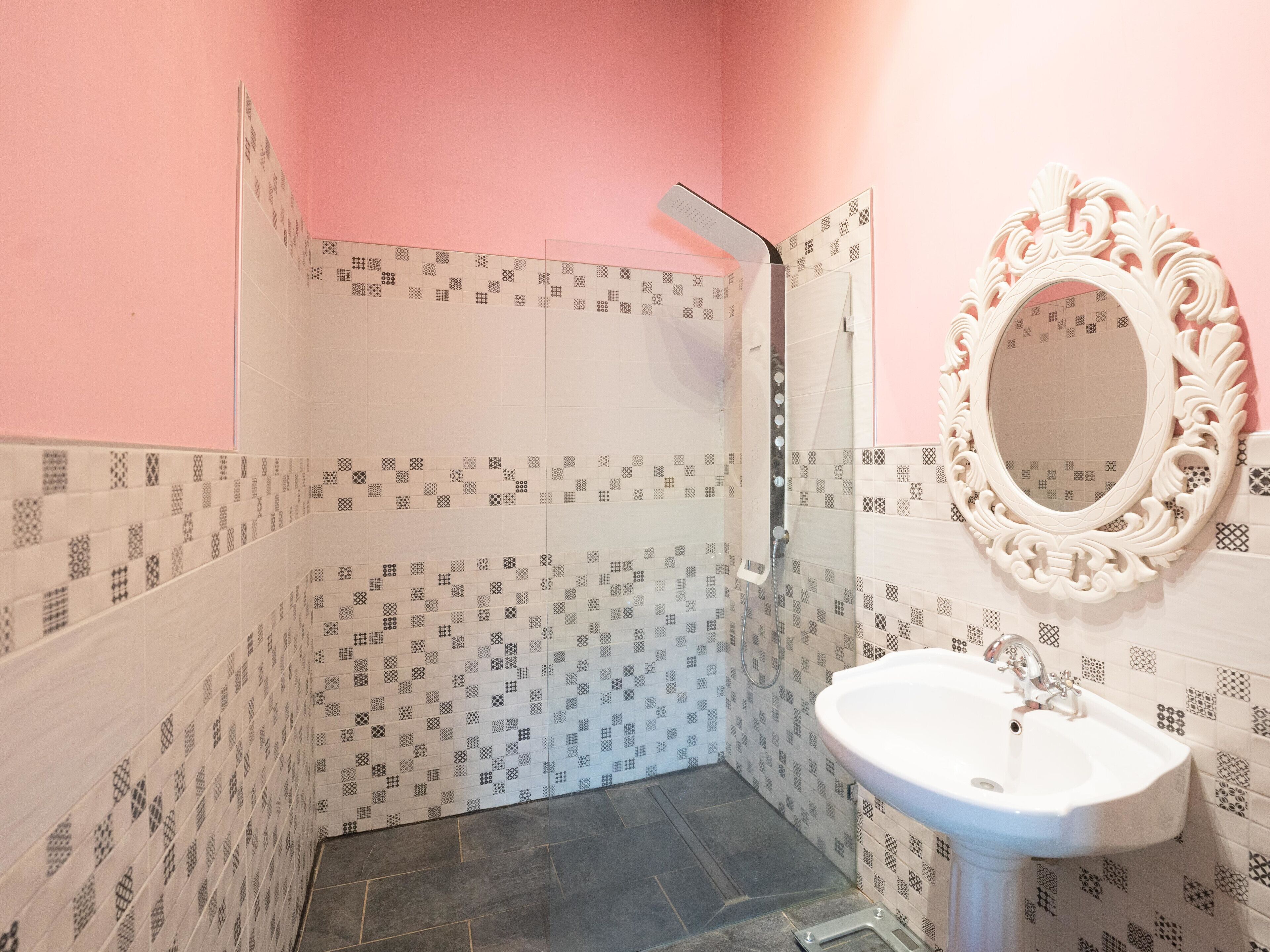 A bathroom with patterned tiles, a shower, a sink, and a decorative mirror.