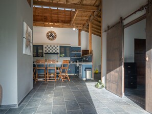Cozinha com teto de madeira, um relógio e um espaço de refeições com cadeiras e mesa.