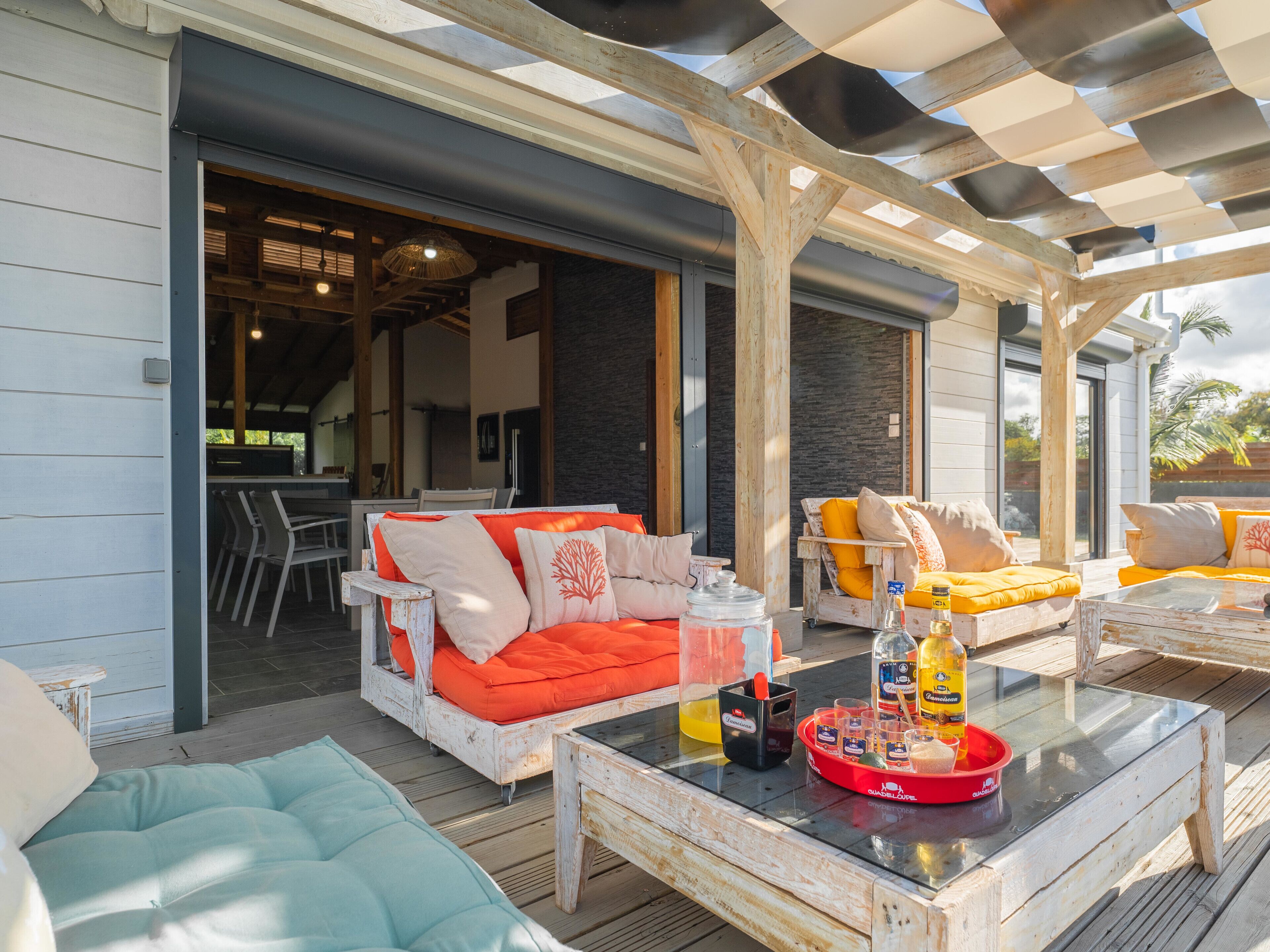 Een buitenpatio met een witte bank, een glazen salontafel en een eettafel.