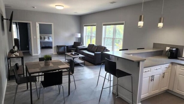 A modern kitchen with a dining area, a sofa, and a coffee machine.