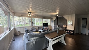 A cozy living room with a large sectional sofa, a wooden coffee table, and a stone fireplace. - Osito Cabin - Pet Friendly | Hot Tub | Fire Pit | Ms. Pac Man | Telescope (Angel Fire)