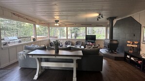 A cozy living room with a fireplace, a dining table, and a sofa. - Osito Cabin - Pet Friendly | Hot Tub | Fire Pit | Ms. Pac Man | Telescope (Angel Fire)