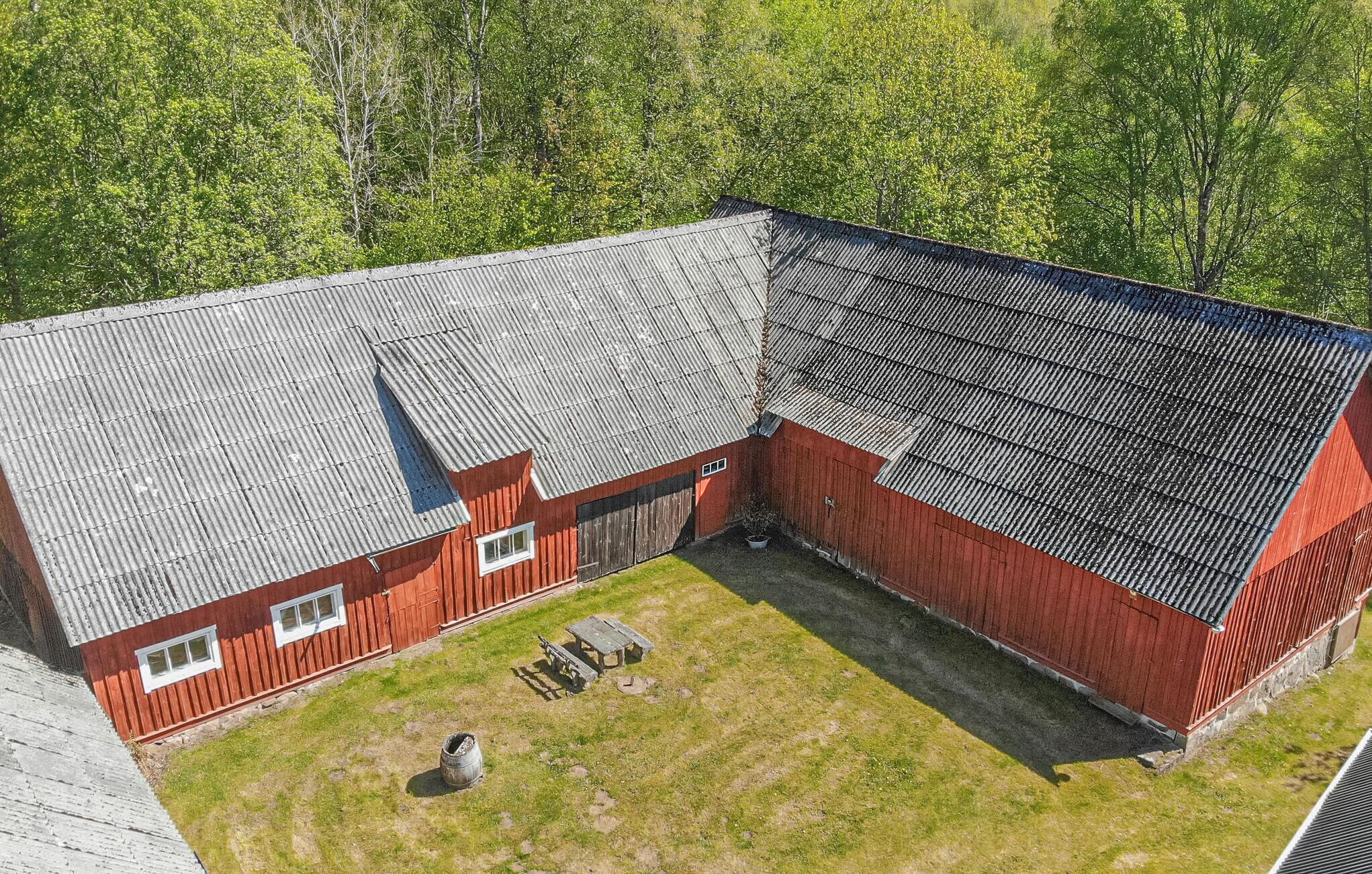 A red barn with a sloped roof and a fenced yard.