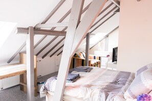 A bedroom with a sloped ceiling, a bed with a lace bedspread, a wooden bench, and a radiator. - BoHo - Jacuzzi, Sauna, BBQ, Garden close to Amsterdam & Utrecht - Sleeps 24 (Kockengen)