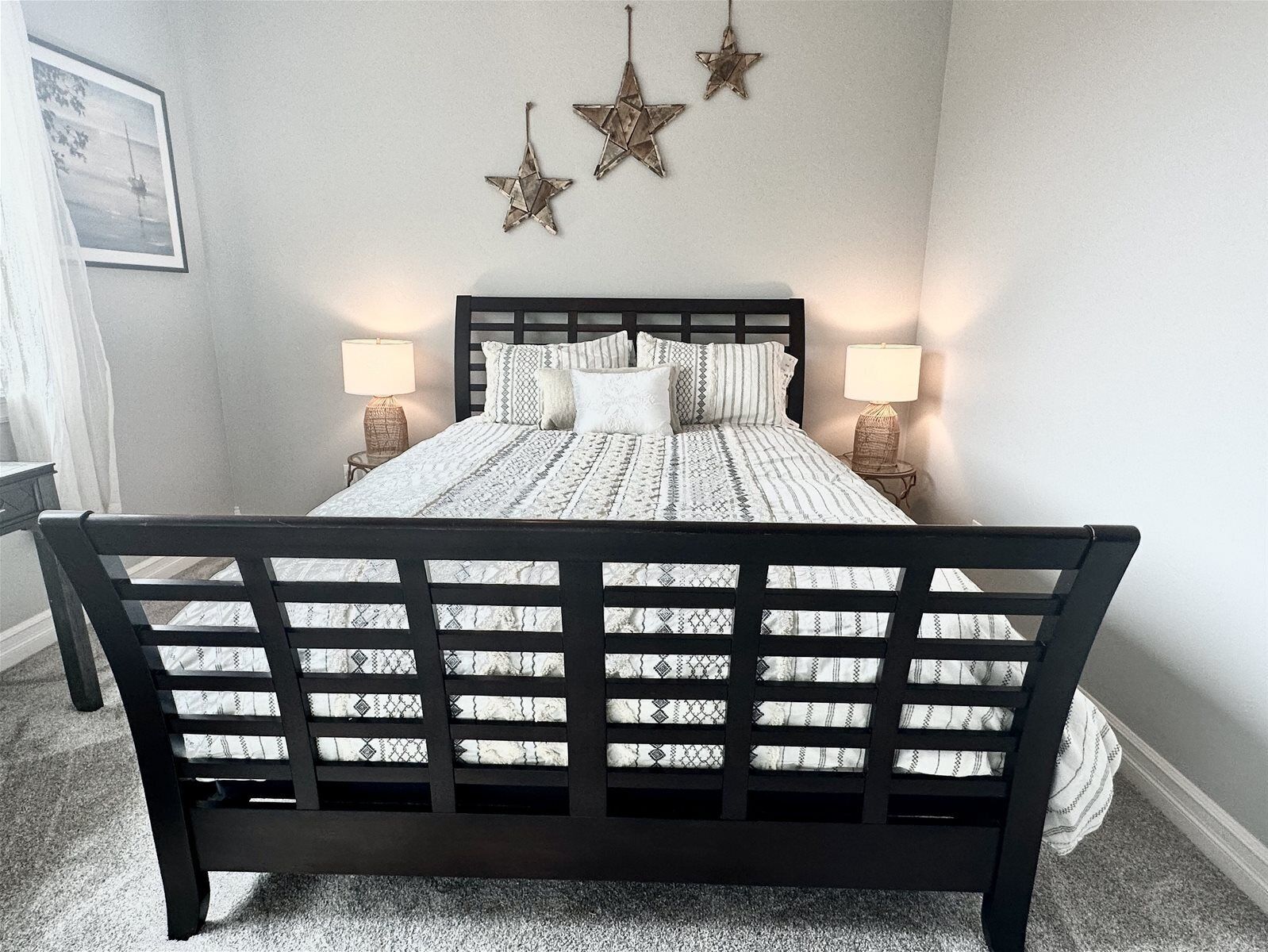 Un dormitorio con cama, dos lámparas de noche, un adorno con forma de estrella en la pared y un cuadro enmarcado.
