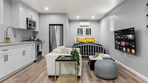 A modern kitchen with white cabinets, a microwave, and a stainless steel refrigerator. - New Studio - Walk to Golden 1 / Old Sac / DOCO (West Sacramento)