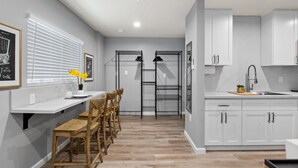 A modern kitchen with white cabinets, a wooden dining table, and chairs. - New Studio - Walk to Golden 1 / Old Sac / DOCO (West Sacramento)