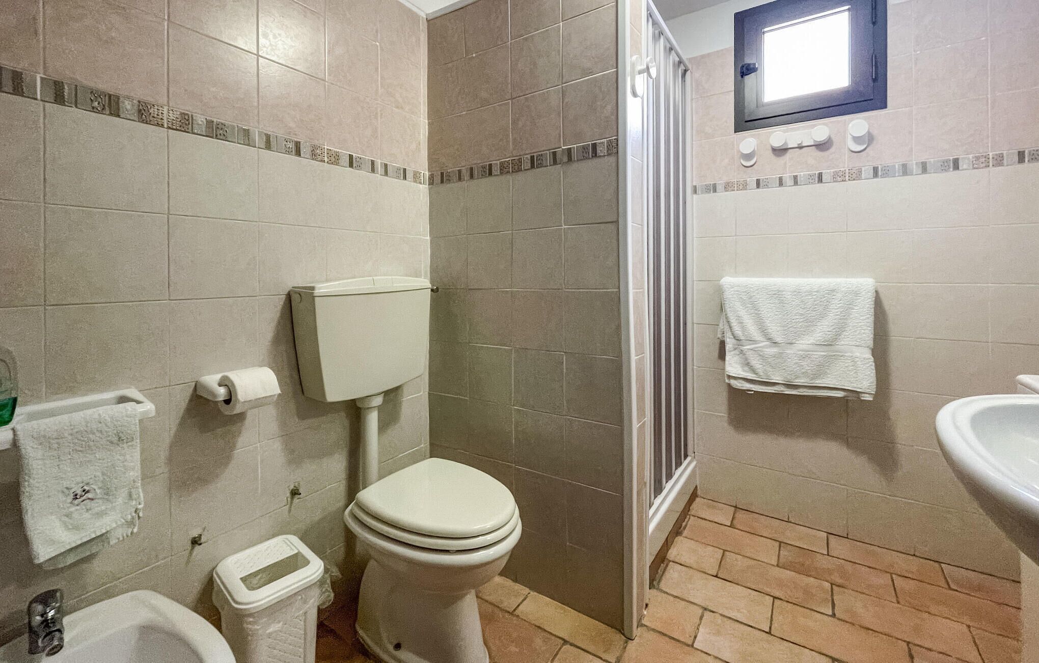 A bathroom with a toilet, bidet, sink, and a shower area.