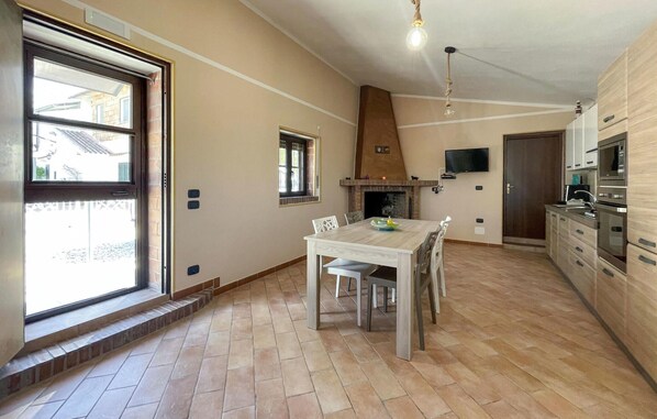 Eine geräumige Küche mit Essbereich, Kamin und Wand-Fernseher.