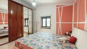 Ein Schlafzimmer mit einem Bett, einem Schrank, einem Fenster und einem Spiegel.