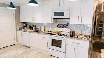 Una cocina moderna con armarios blancos, un microondas, un horno y un salpicadero con estampado en espiga.