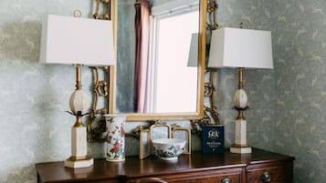 A wooden dresser with two wall-mounted lamps, a mirror, a vase, a bowl, and a framed certificate.