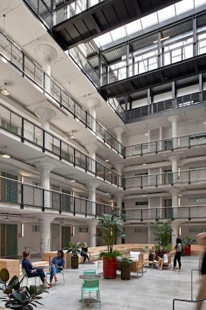 A multi-level atrium with open spaces, seating areas, and potted plants. - Goldenrod by Pettigrew Adventures @ Crosstown (Memphis)