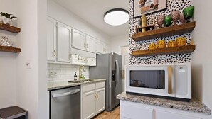 A modern kitchen with white cabinets, stainless steel appliances, and a microwave on a granite countertop.