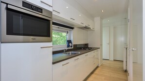 Cocina moderna con microondas integrado, pileta de acero inoxidable y ventana con vista a follaje.