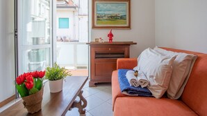 A living room with a wooden table, a sofa, a potted plant, and a painting on the wall.