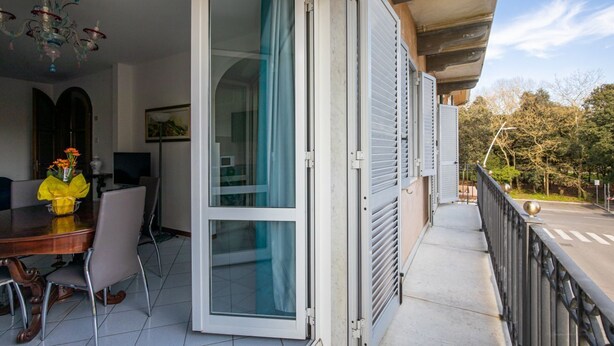 A balcony with a sliding glass door, a dining area with a table and chairs, and a chandelier.