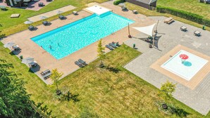 A large rectangular swimming pool with a sunshade, surrounded by lounge chairs and a small deck area. - 3 bedroom gorgeous home in Zorgvlied (Zorgvlied)