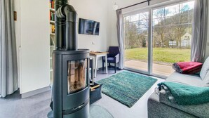 A modern living room with a black wood-burning stove, a flat-screen TV, a dining table, and a sofa. - Awesome home in Clausthal-Zellerfeld with WiFi (Clausthal-Zellerfeld)