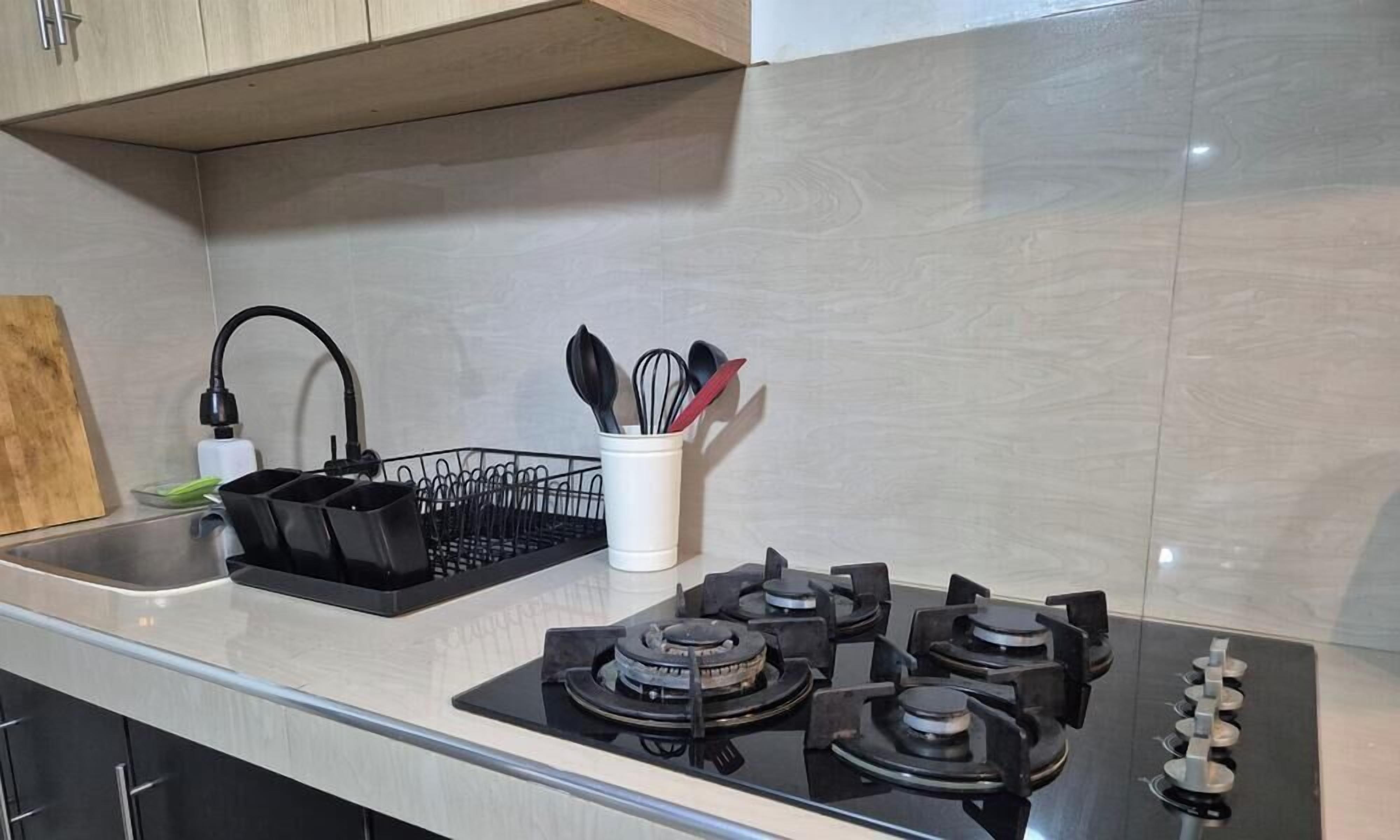 A kitchen with a gas stove, a sink, and a utensil holder.