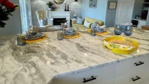 Una cocina moderna con encimera de mármol, dos lámparas colgantes y horno empotrado.
