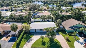 A residential area with houses, a swimming pool, and a lake in the background. - Lovely home with heated Pool a mile from the beach (Boca Raton)