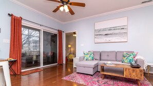A living room with a grey sectional sofa, a wooden coffee table, and a large window with red curtains. - Walk to Outlets & Breweries, Restaurants and community pool (Lewes)