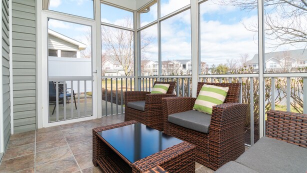 A covered patio with wicker furniture and a glass door leading to a backyard. - Walk to Outlets & Breweries, Restaurants and community pool (Lewes)