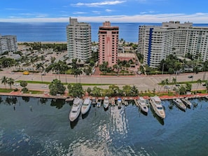 Un port de plaisance où sont amarrés plusieurs yachts, entouré de grands immeubles et offrant une vue dégagée sur l’océan.