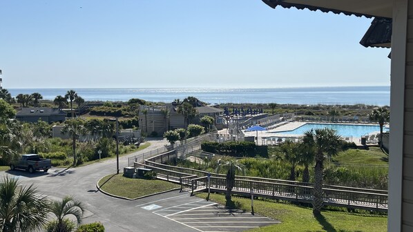 A resort with a swimming pool, a parking area, and a view of the ocean.