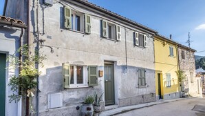 A two-story building with a green door, multiple windows with shutters, and a small garden area with potted plants. -  A26 - Poggio, sky-land with breathtaking sea view (Ancona)