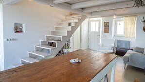 A wooden dining table with a plate, white stairs, a white chair, and a sofa in a room with white walls and a wooden ceiling. -  A26 - Poggio, sky-land with breathtaking sea view (Ancona)