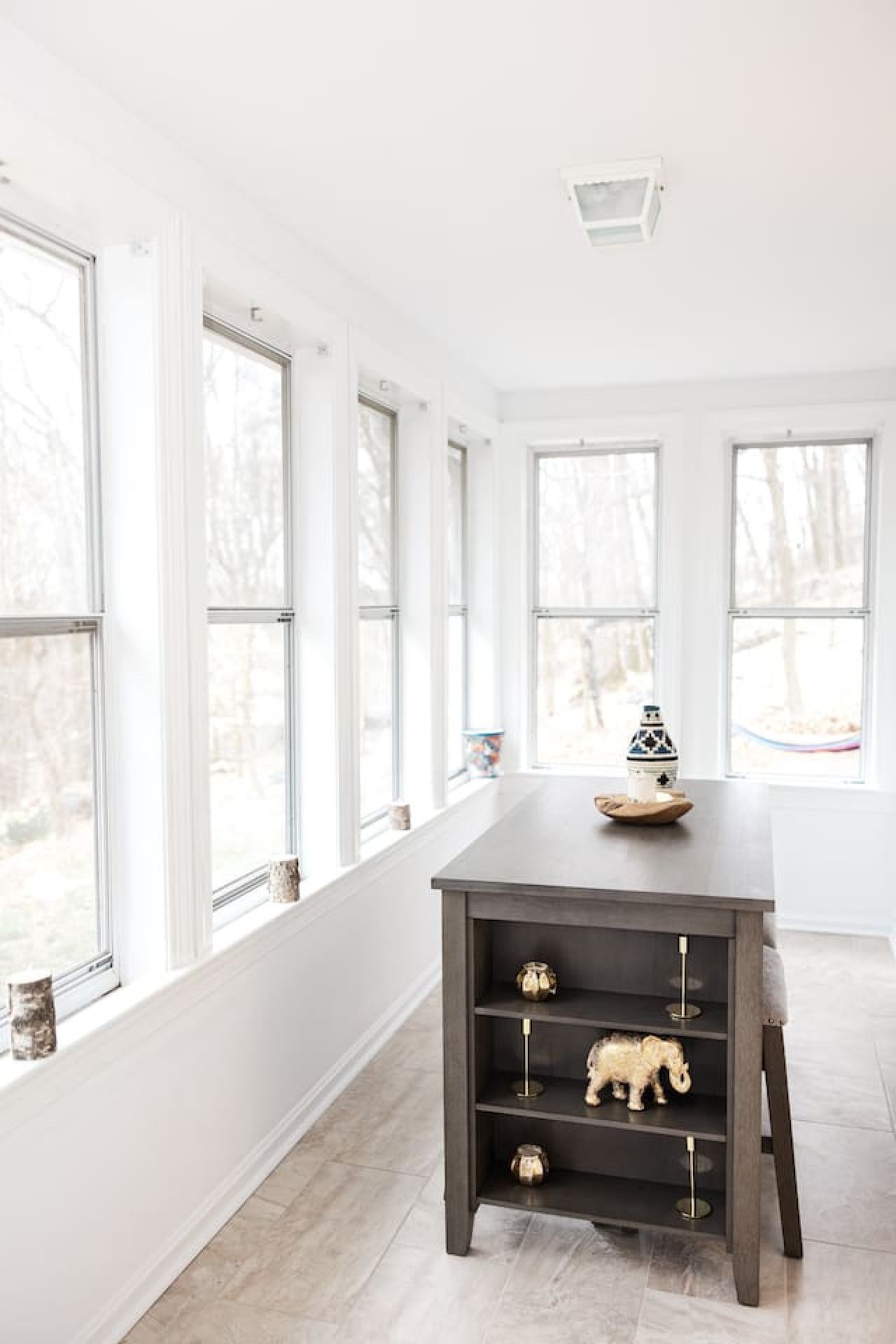 A modern interior with a dark wooden table, shelves, and large windows.