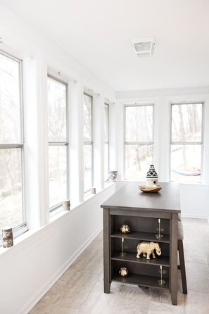 Ein modernes Interieur mit einem dunklen Holztisch, Regalen und großen Fenstern.