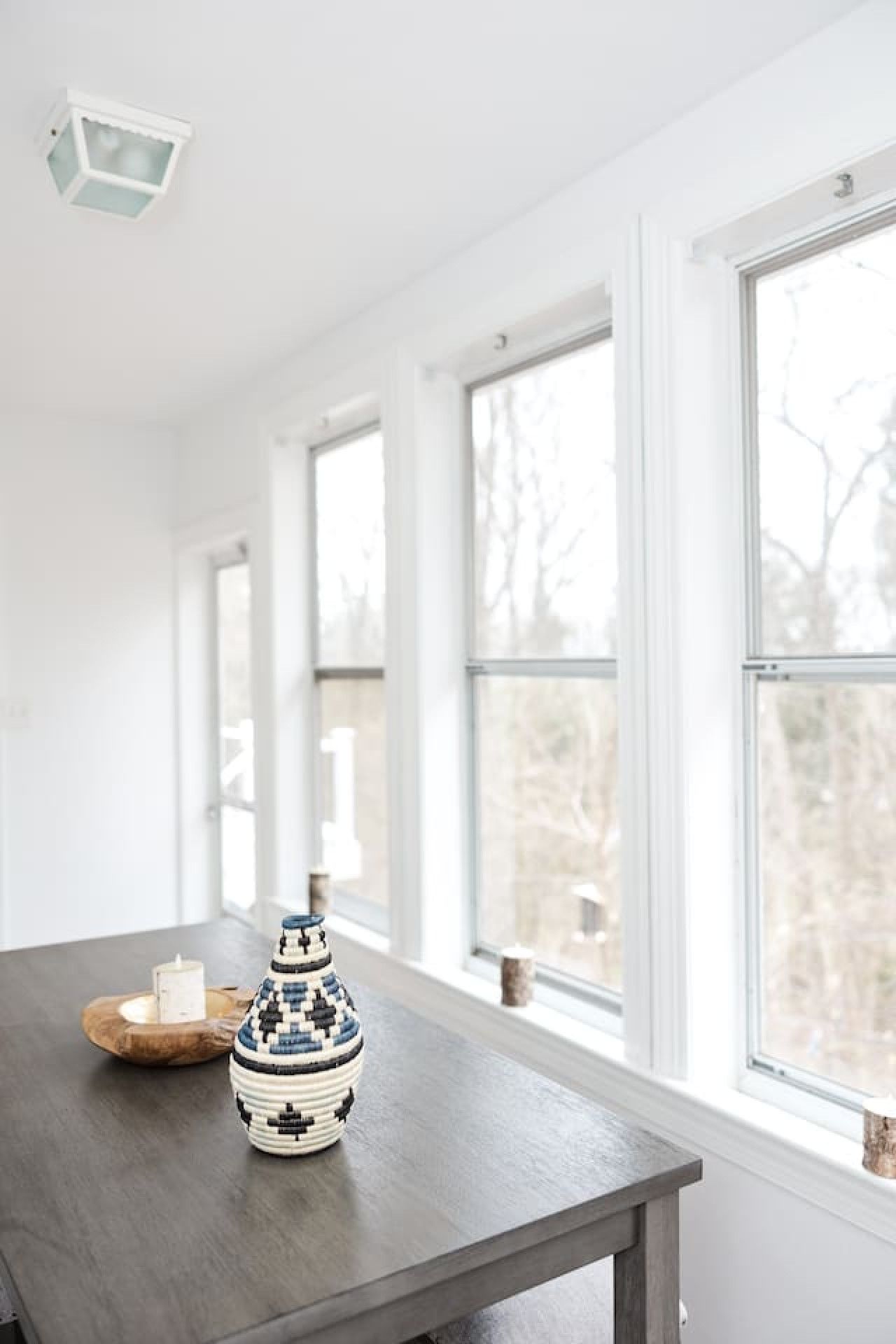 A room with a long table, a decorative vase, and a candle on a tray.
