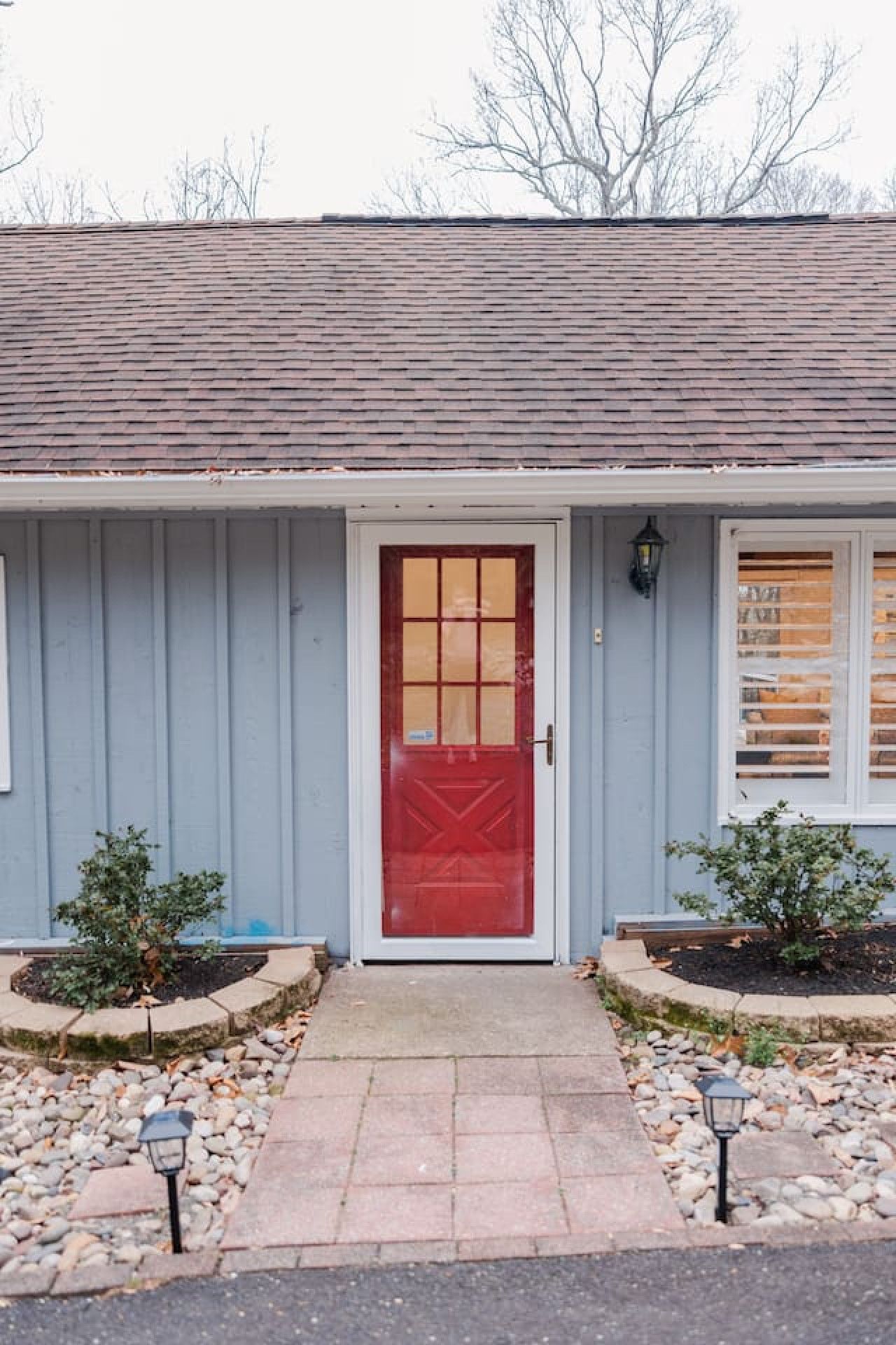 A house with a red door, a small porch, and two potted plants.