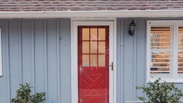 A house with a red door, a small porch, and two potted plants.