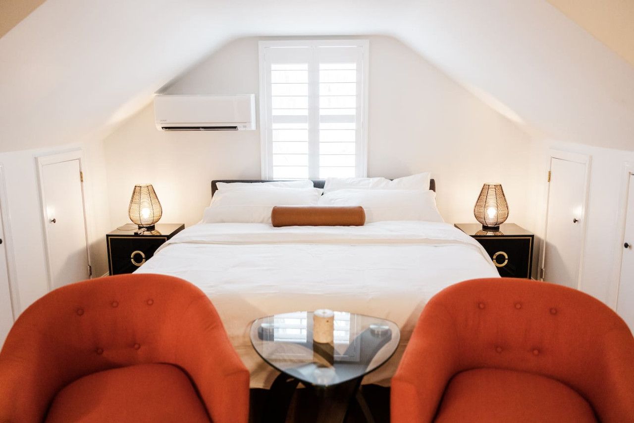 A bedroom with a bed, two nightstands, a table, and two chairs.