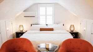 A bedroom with a bed, two nightstands, a table, and two chairs. - Cowry Acres - The First House Villa w Hot Tub (New Hope)