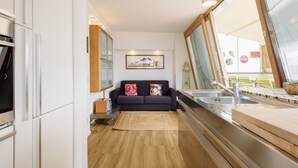 Una cocina moderna con un ventanal grande, un sofá con cojines coloridos y un comedor con mesa de madera.