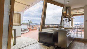 Una cocina moderna con un ventanal grande, un televisor de pantalla plana y vistas a un paisaje urbano.
