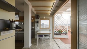 Una cocina compacta con electrodomésticos modernos, un comedor con mesa y sillas, y un balcón con vistas.