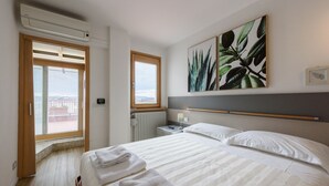 Una habitación de hotel con una cama, una ventana, un radiador y un termostato.